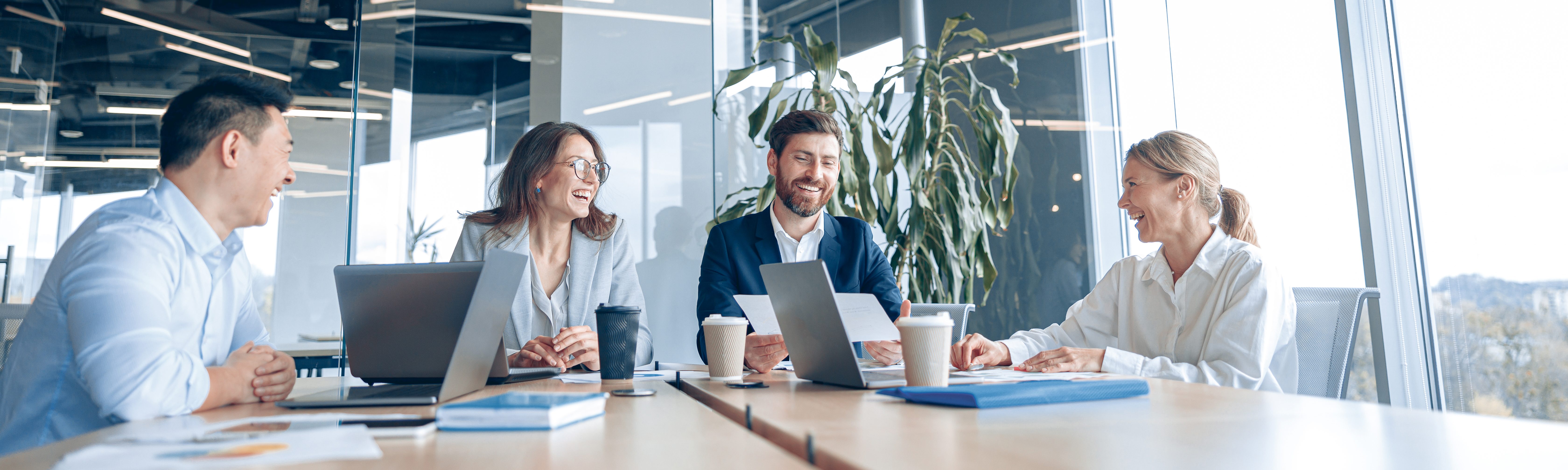 Business professionals smiling during a meeting around a table in a modern office