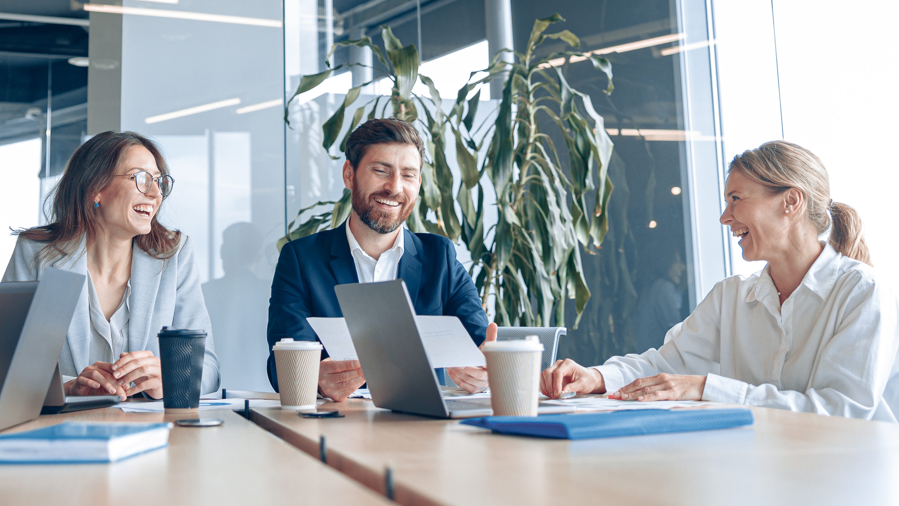 Business professionals smiling during a meeting around a table in a modern office