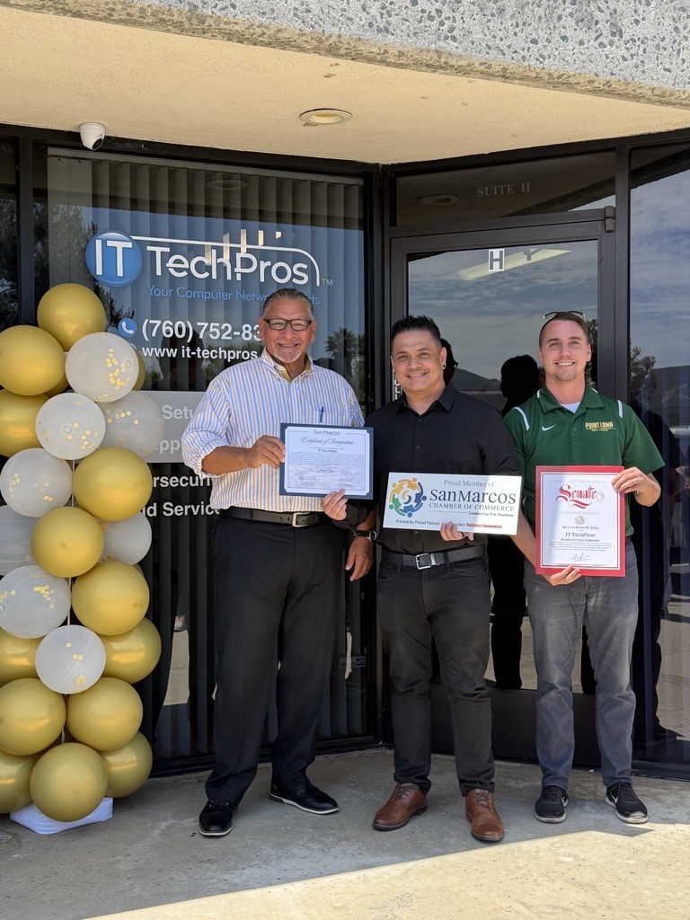 Group photo outside IT TechPros office, featuring four men holding certificates, with a balloon decoration in the background.